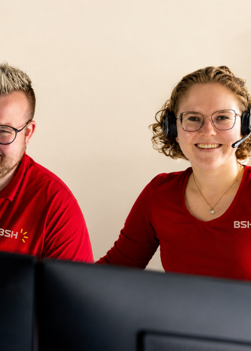 2 Mitarbeitende von BSH mit rotem Oberteil vor einem Laptop sitzend