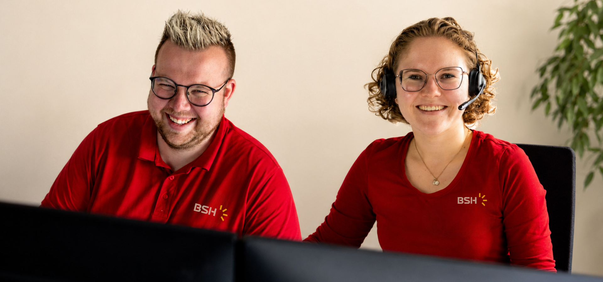 2 Mitarbeitende von BSH mit rotem Oberteil vor einem Laptop sitzend